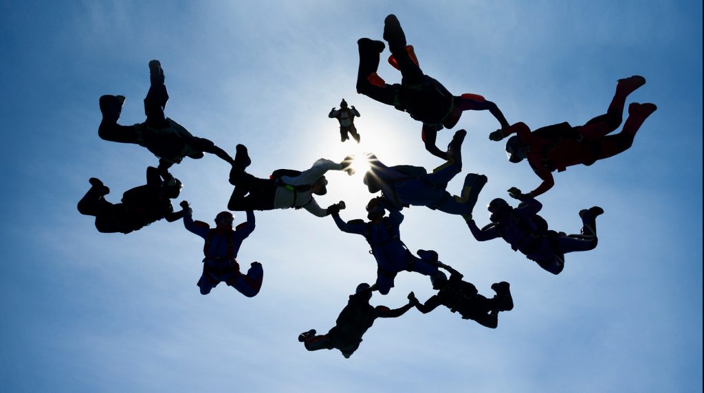 Group of skydivers forming a circle by holding hands in midair.