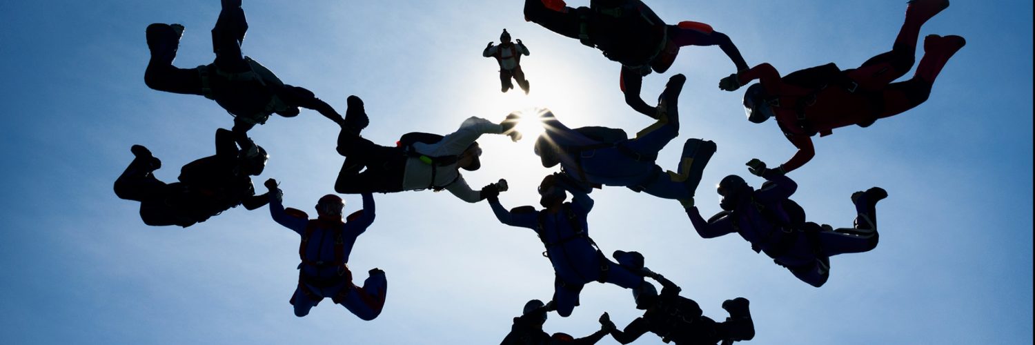 Group of skydivers forming a circle by holding hands in midair.