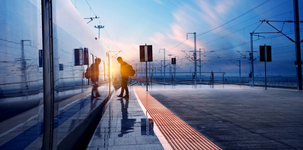 Train passenger entering train at railroad station at sunset