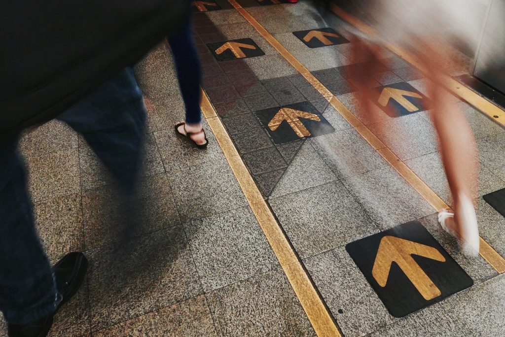 ground shot of people's feet while walking on busy arrow lined pathway